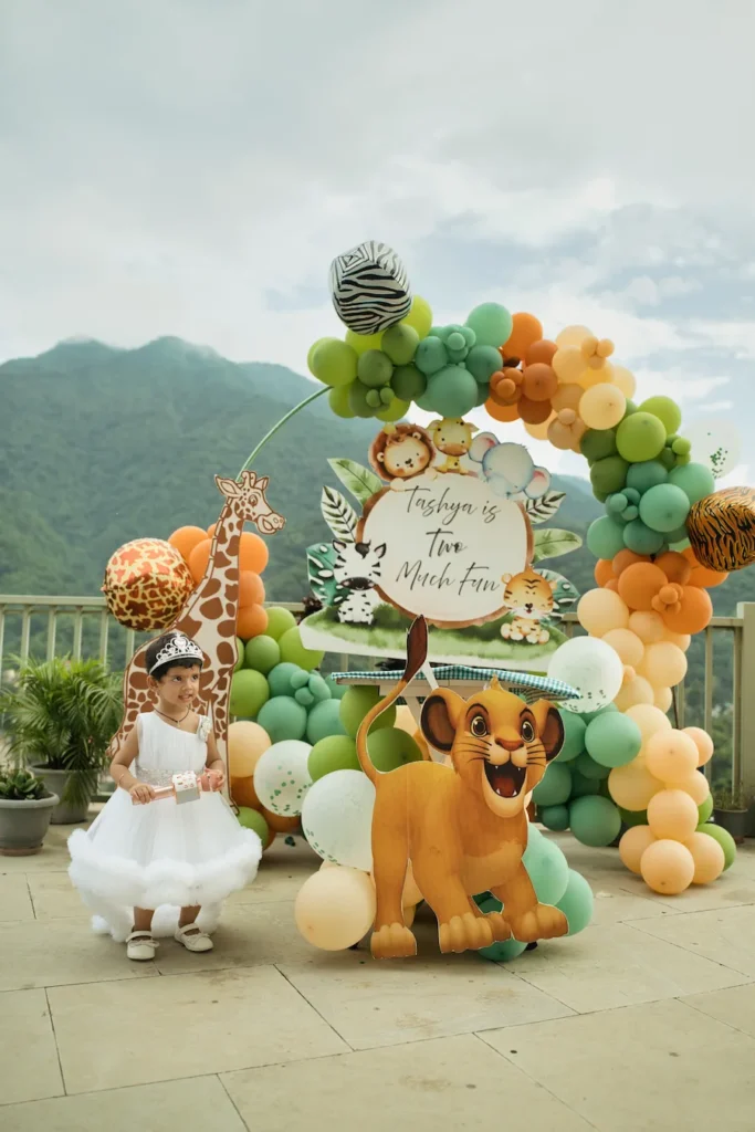 First birthday photoshoot with a jungle safari theme featuring a baby girl and colorful balloon decorations