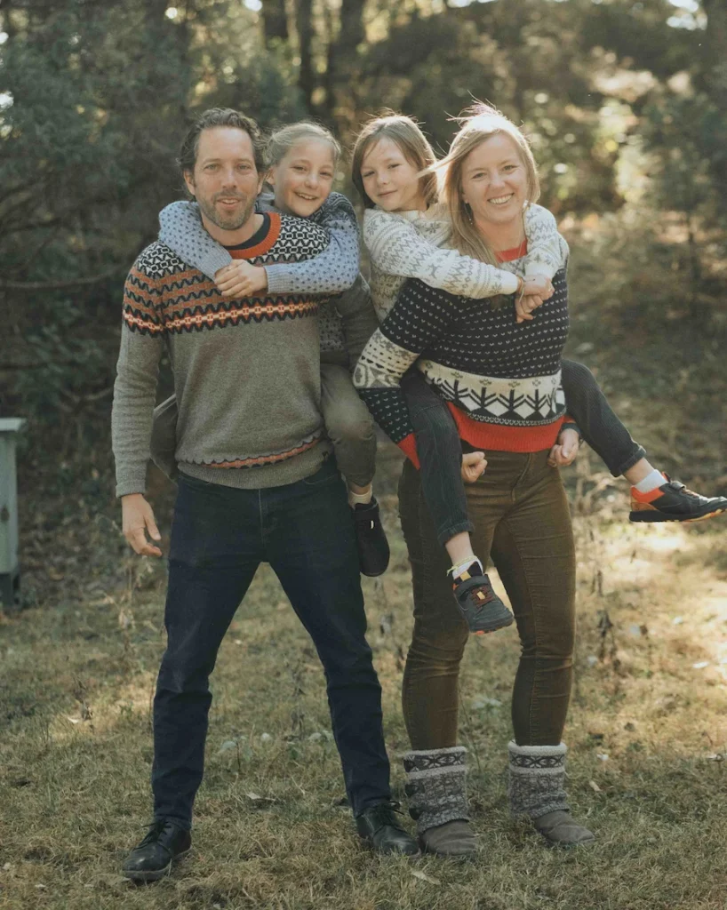 Parents carrying their children while smiling together in a beautiful outdoor setting surrounded by the hills of Mussoorie.