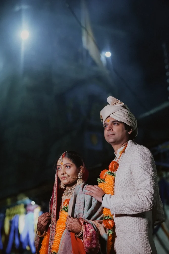 Bride and groom standing together during an evening ceremony at Triyuginarayan Temple.