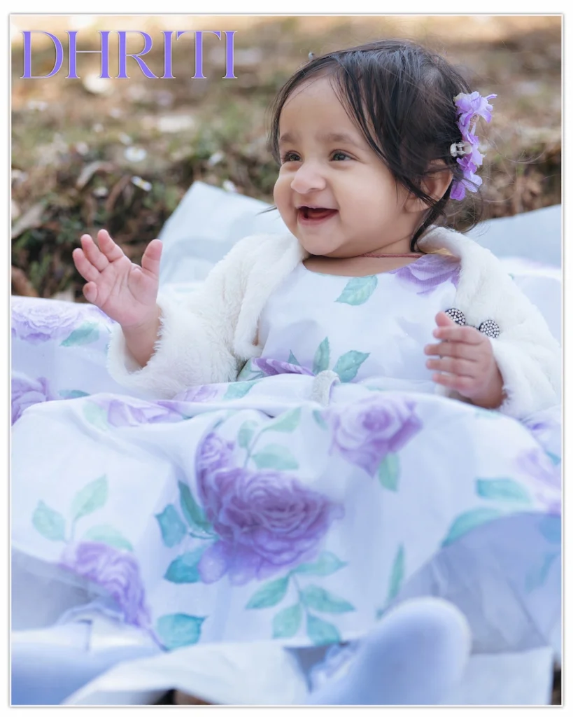 Happy baby girl wrapped in a floral blanket enjoying an outdoor portrait session