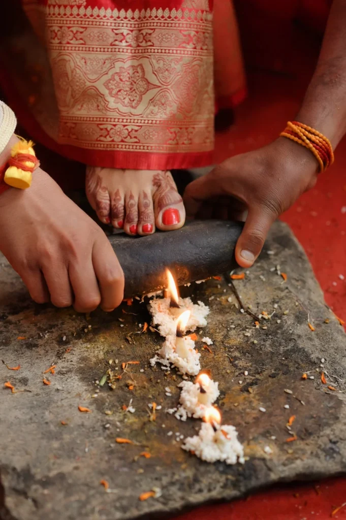 Bride placing her foot on the ceremonial stone during a traditional Hindu wedding ritual.