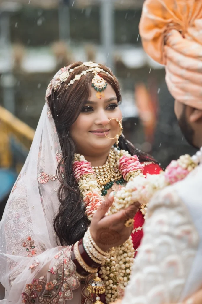 Bride smiling during the garland exchange ceremony with traditional bridal jewelry.
