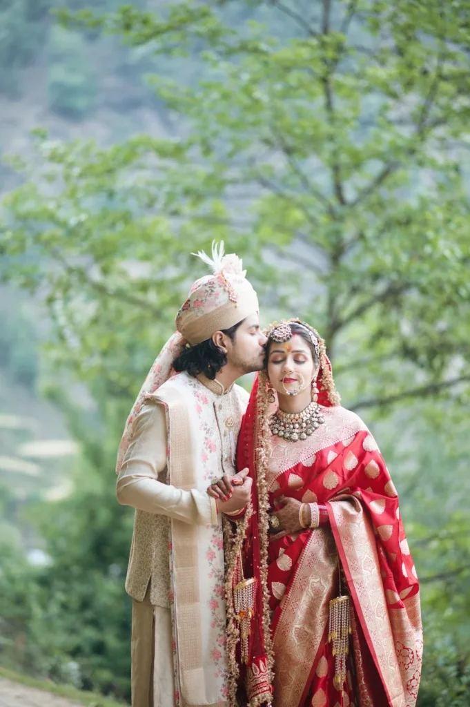 Groom kissing the bride's forehead in a peaceful outdoor portrait after the ceremony.