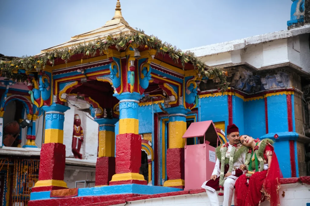 Traditional Ukhimath wedding couple portrait captured near the colorful temple pavilion at Omkareshwar Temple.