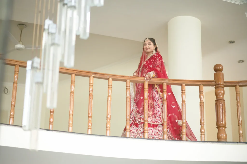 Bride getting Married in Dehradun posing on a luxury venue balcony in traditional red bridal attire