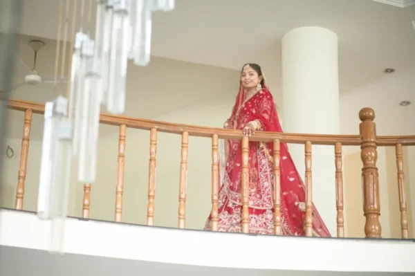 Bride getting Married in Dehradun posing on a luxury venue balcony in traditional red bridal attire