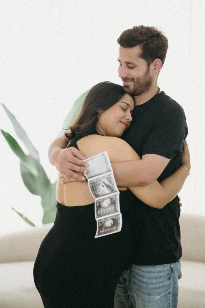 Expecting parents sharing a heartfelt moment while holding ultrasound scan photos