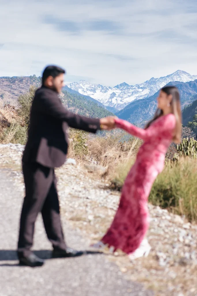 Romantic couple photoshoot on a mountain road with panoramic Himalayan views creating a dreamy backdrop.