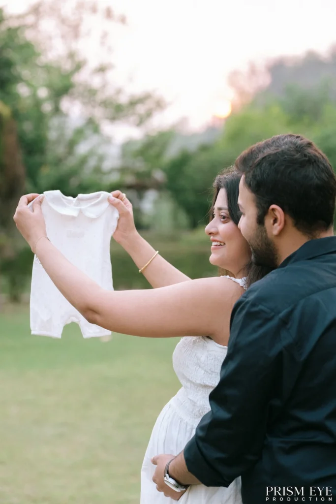 Couple holding baby clothes while preparing to welcome their newborn