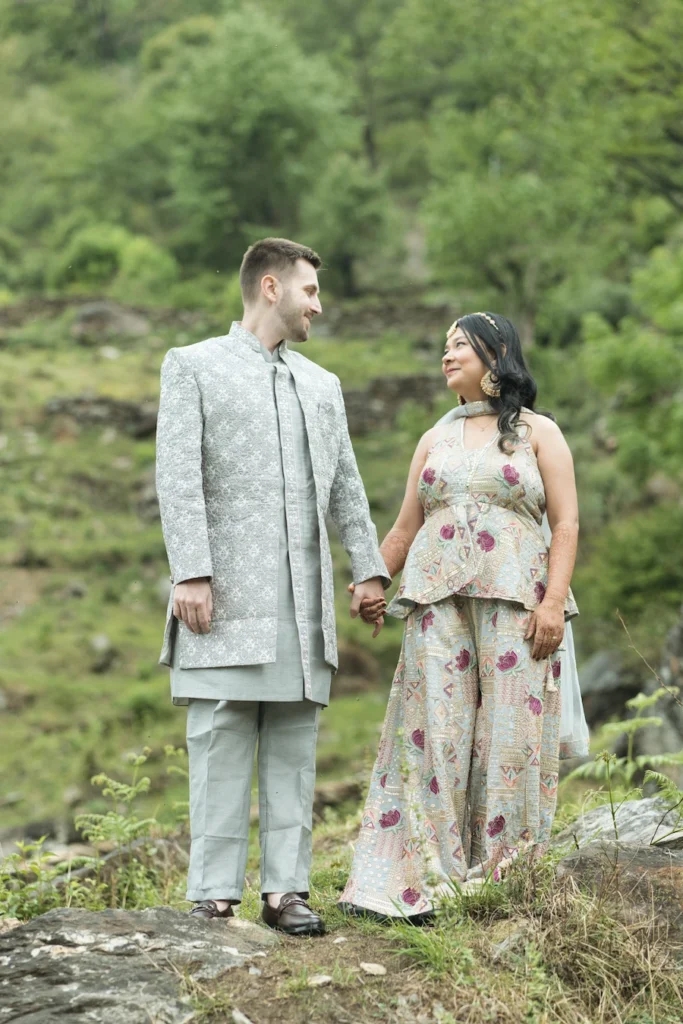 Couple holding hands during a romantic portrait session surrounded by lush green hills
