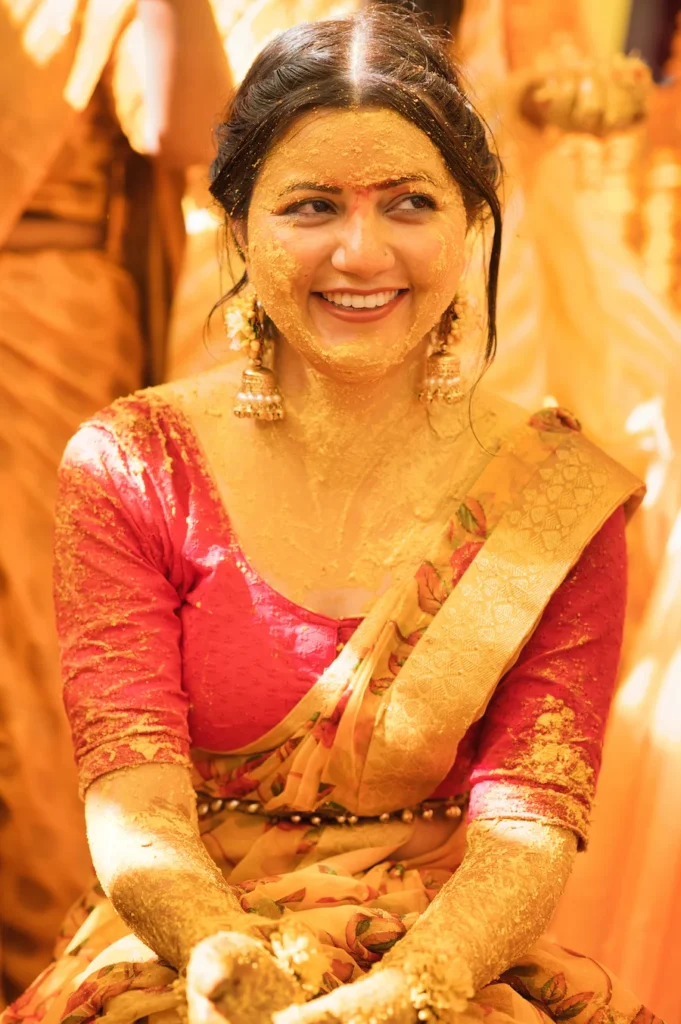 Smiling bride covered in turmeric during a joyful haldi ceremony surrounded by family traditions