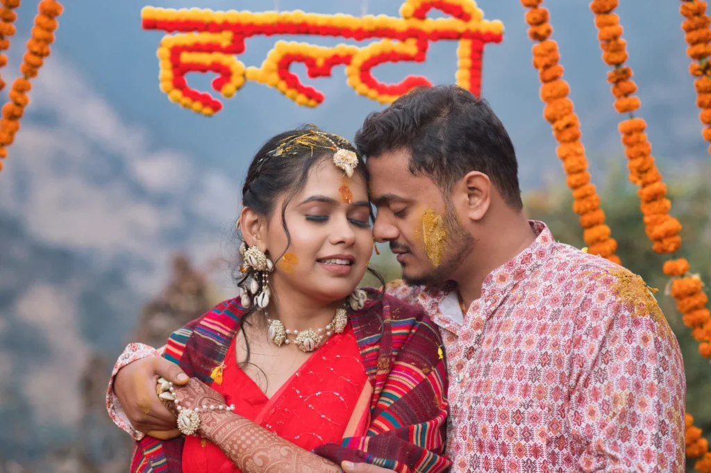 Couple embracing during a colorful haldi ceremony decorated with marigold flowers and festive details