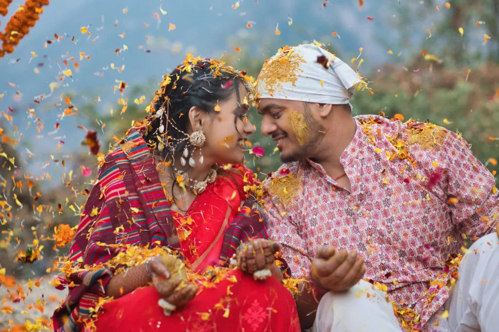 Bride and groom sharing a candid moment amid flower petals during a joyful pre-wedding ritual