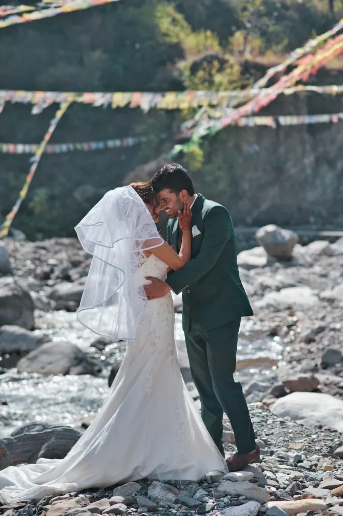 Bride and groom sharing an intimate moment beside a mountain river during a romantic wedding portrait
