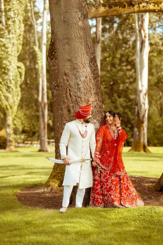 Bride and groom posing beneath a large tree during their wedding