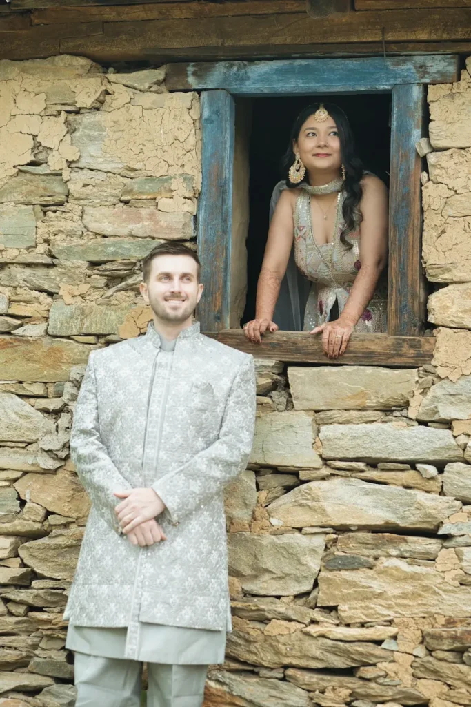 Bride and groom posing at a rustic stone house during a destination wedding photoshoot in the mountains