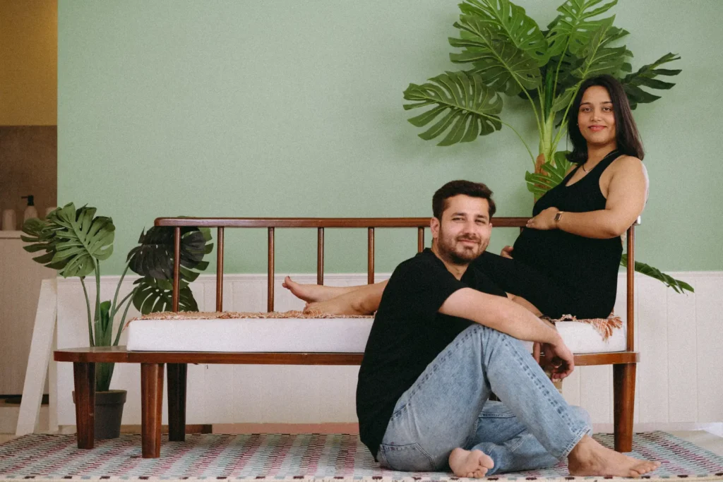 An expecting couple posing together in a modern, stylish home setting, capturing a cozy and relaxed lifestyle vibe.