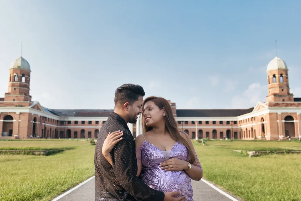 A beautiful maternity portrait of an expecting couple sharing a loving moment in front of a grand heritage building.