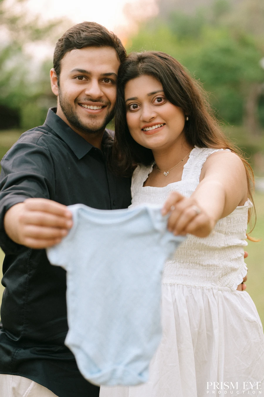 Already making room in their hearts for the tiniest member of the family. Expecting couple holding a baby outfit during a maternity photoshoot