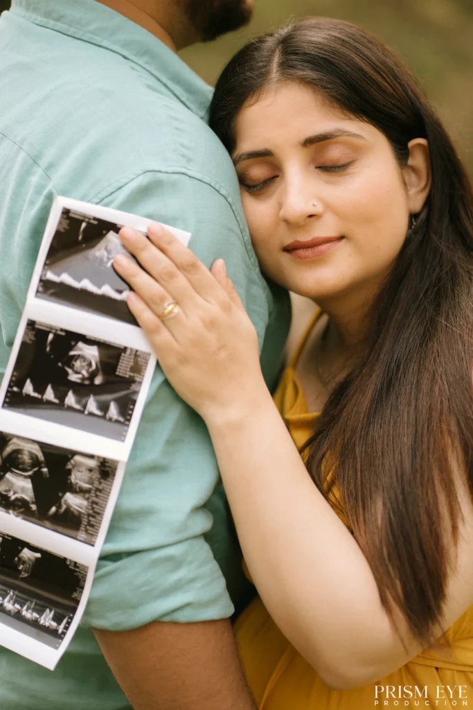 Expecting mother holding ultrasound photos while resting beside her partner
