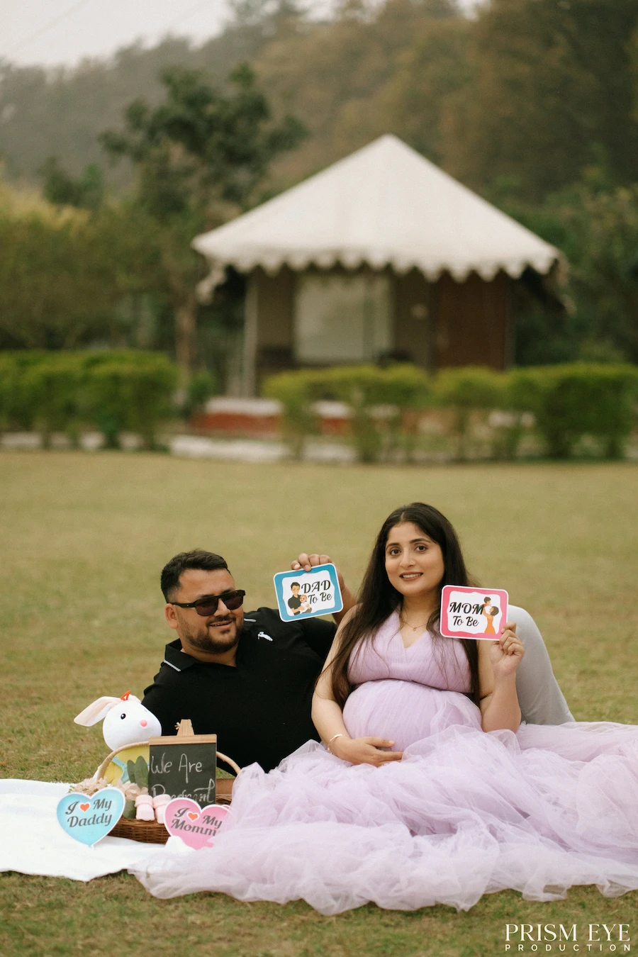 Mom-to-be, Dad-to-be, and a little love story waiting to begin. Expecting couple holding parent-to-be signs during an outdoor maternity photoshoot