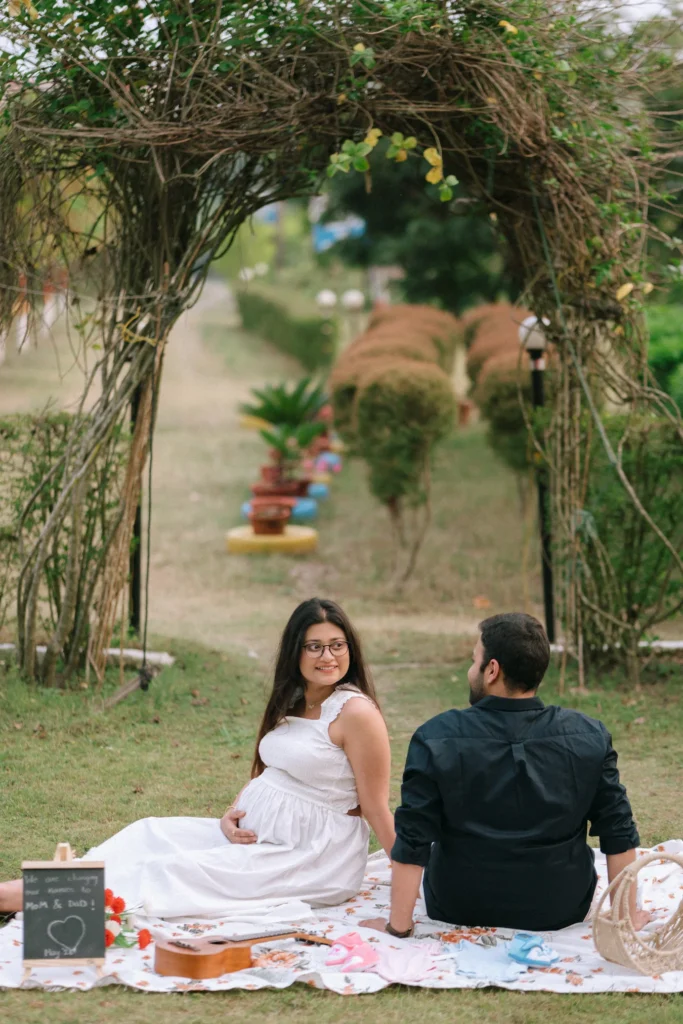 An expectant couple enjoying a candid maternity picnic under a natural archway in Shivpuri, Rishikesh.