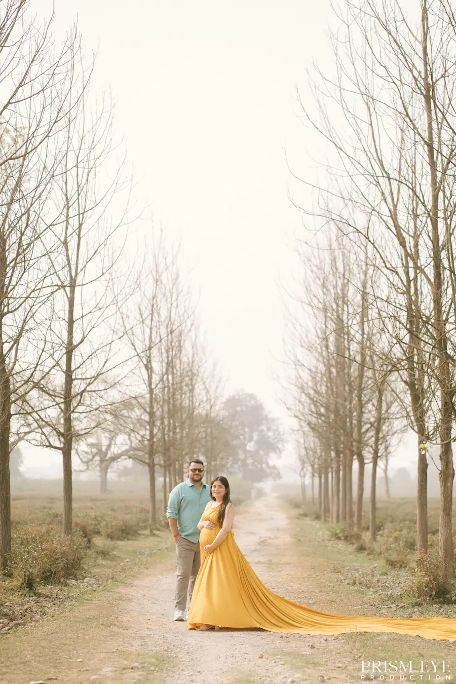 Walking into a beautiful new chapter, one step at a time. Expecting couple walking along a tree-lined path during a maternity photoshoot in Dehradun