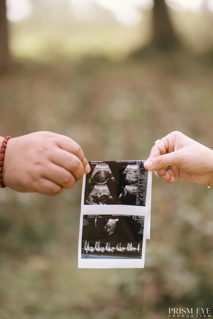 Couple holding an ultrasound photo during an outdoor maternity photoshoot