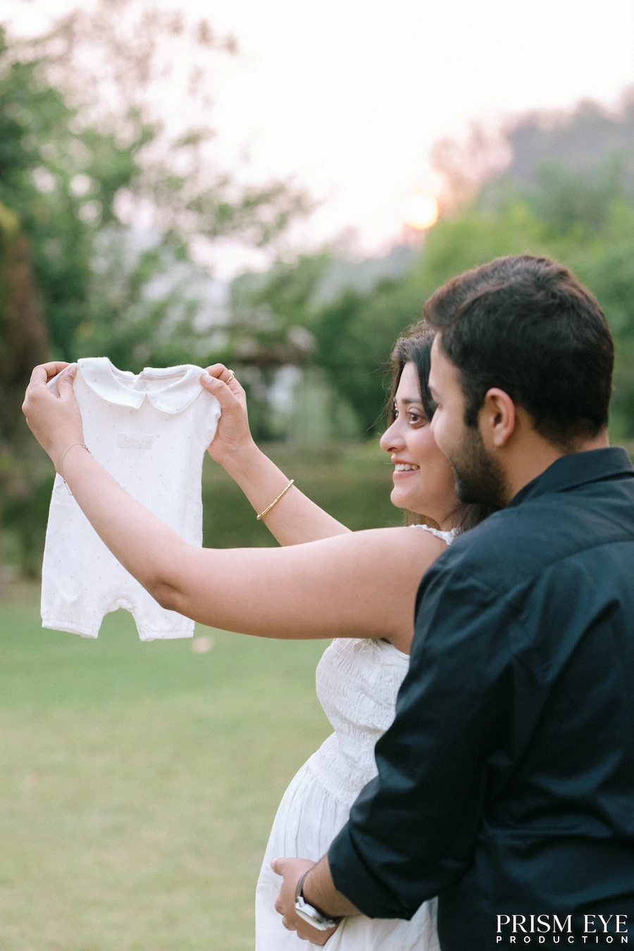 A tiny outfit for the little one who has already filled their hearts with love. Expecting couple holding a baby outfit during an outdoor maternity photoshoot in Uttarakhand