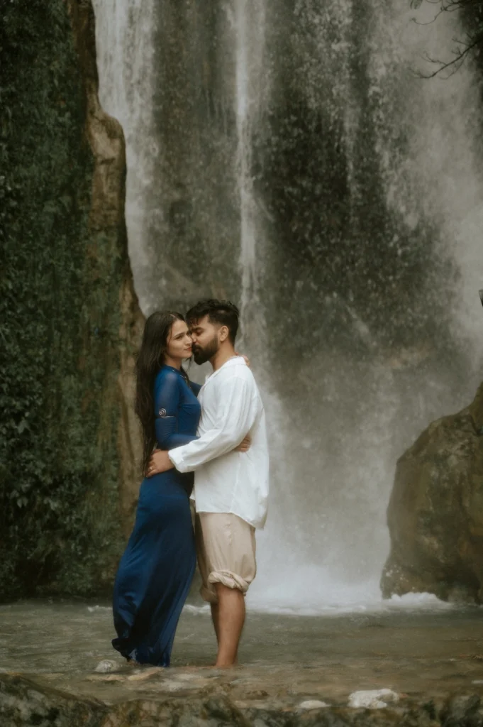 Couple embracing in front of Bhatta Falls during an adventurous pre-wedding shoot in Mussoorie