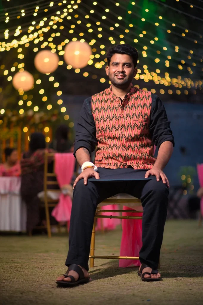 Groom portrait captured during an evening wedding celebration with decorative lights in the background