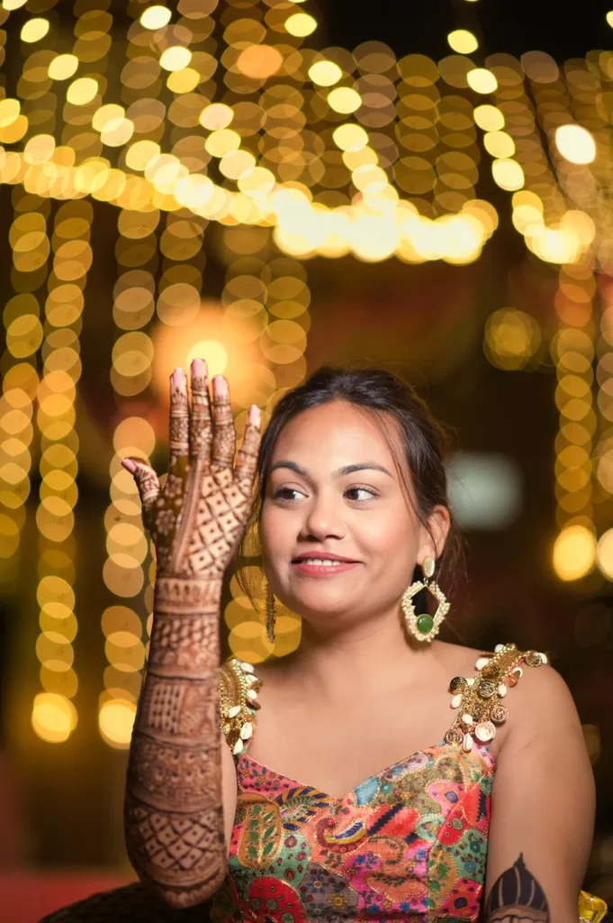 Bride admiring her intricate mehndi artwork during a colorful pre-wedding function