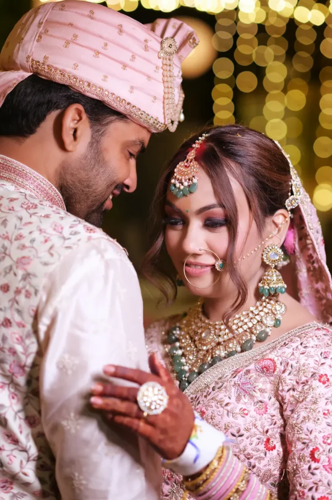Newlywed couple in traditional attire sharing an intimate portrait under warm reception lights