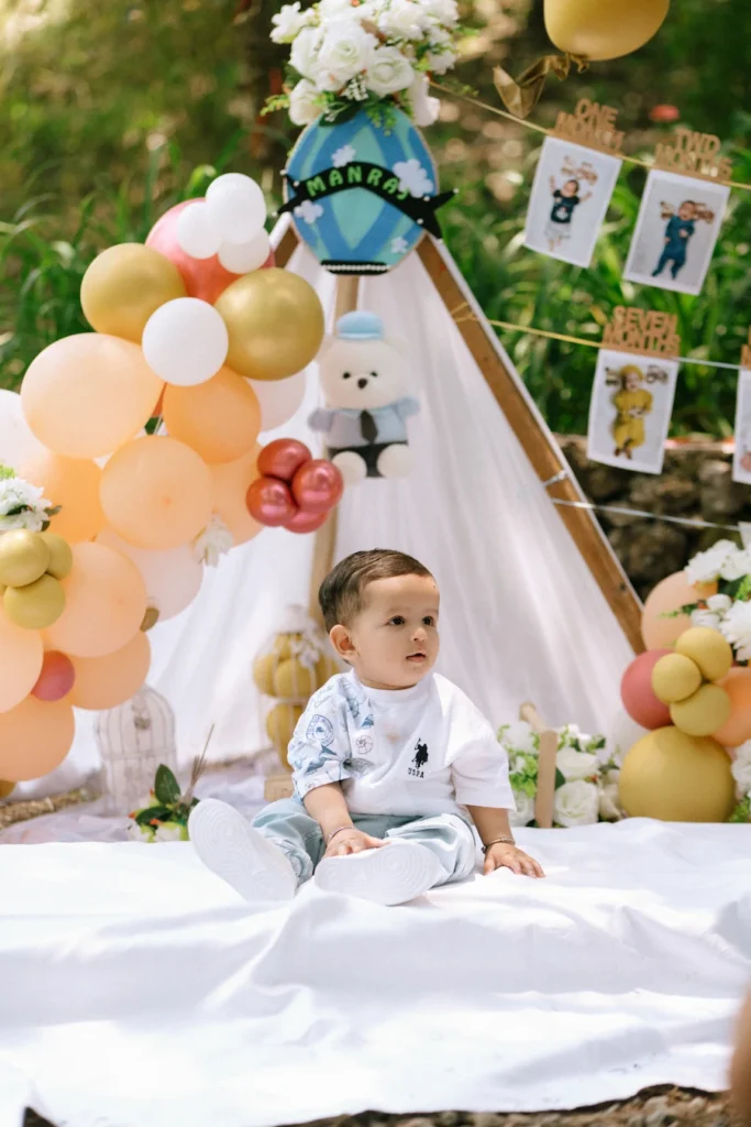 Baby Manraj sitting near pastel balloon decor during his first birthday photoshoot at Hathipaon