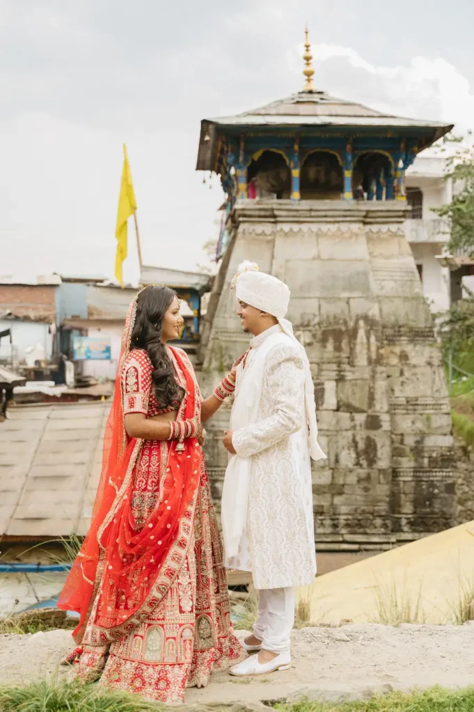 Bride and groom posing together with an ancient stone shrine in the background.