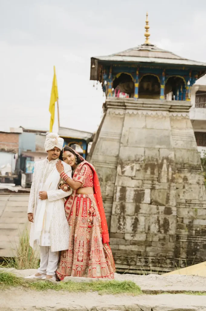 Bride and groom posing together beside an ancient Himalayan wedding shrine.