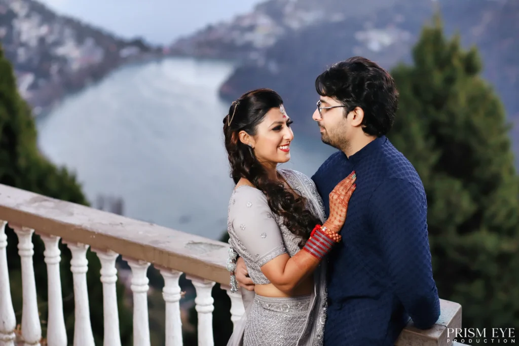 Romantic pre-wedding shoots at a scenic mountain lake featuring a couple sharing a candid moment during a destination photoshoot.