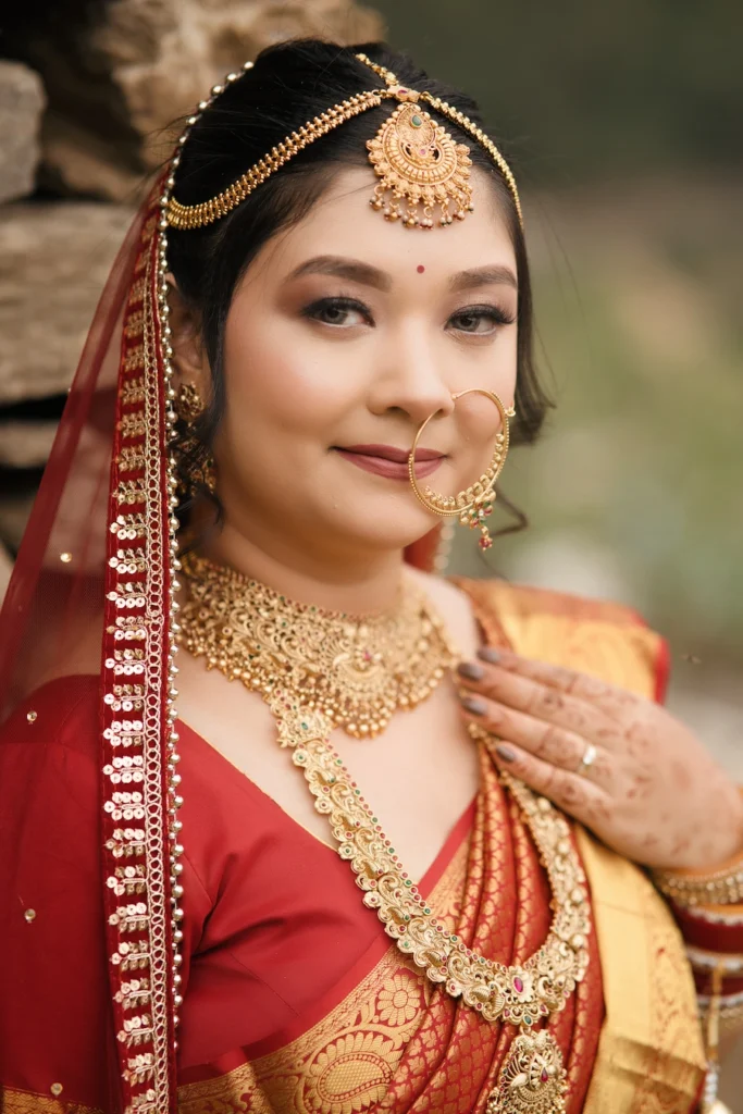Bride in a red saree wearing traditional gold jewelry and bridal headpiece
