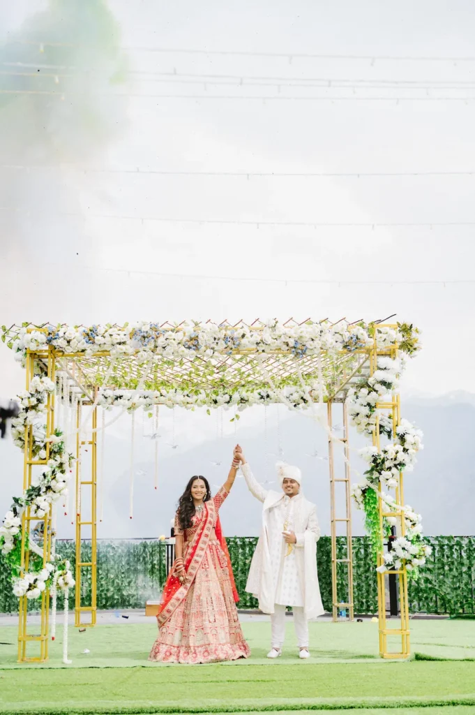 Wedding Photography in Triyuginarayan featuring a bride and groom celebrating beneath a floral wedding arch