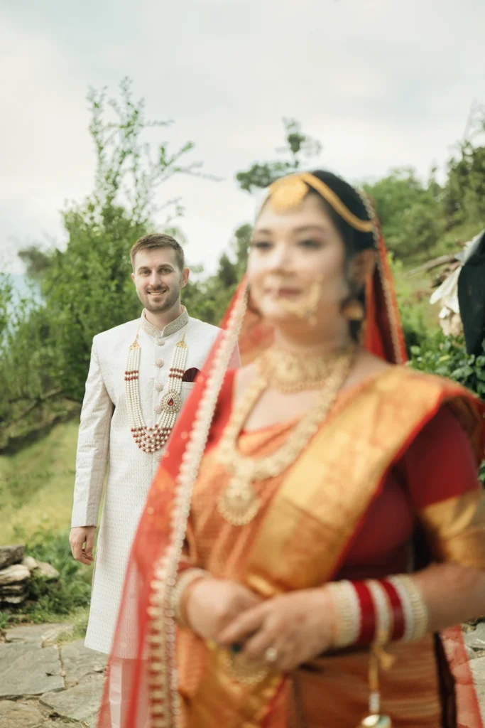 Bride in the foreground with the groom standing behind her during an outdoor wedding portrait