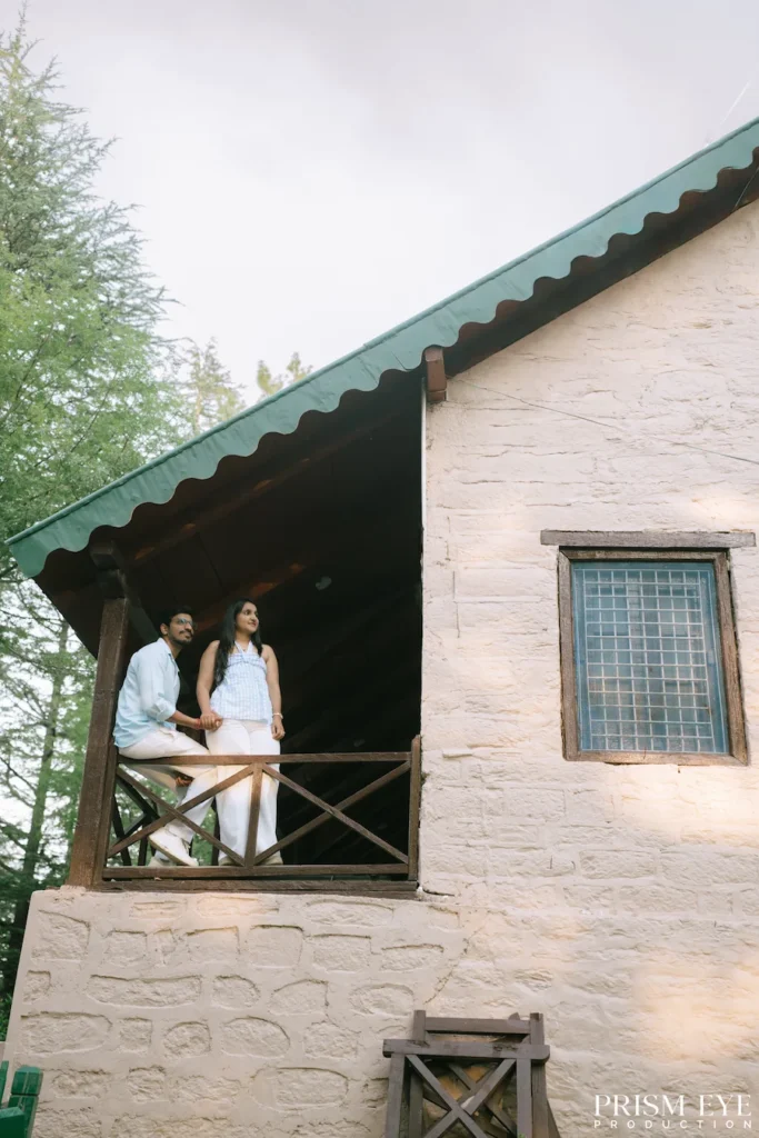 Couple standing on the balcony of a rustic cottage in Koti, Kansar