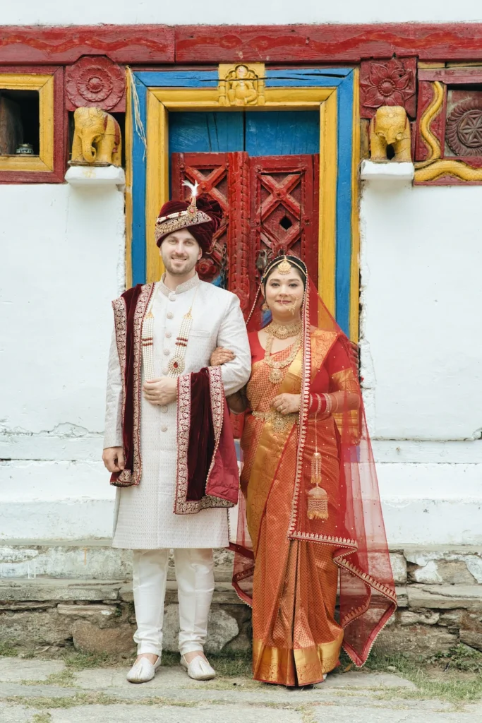 Bride and groom posing together beside a beautifully painted traditional village doorway