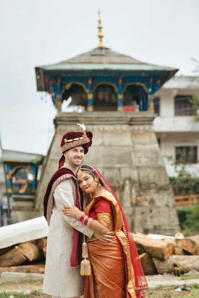 Bride and groom embracing near the traditional temple structure at Triyuginarayan