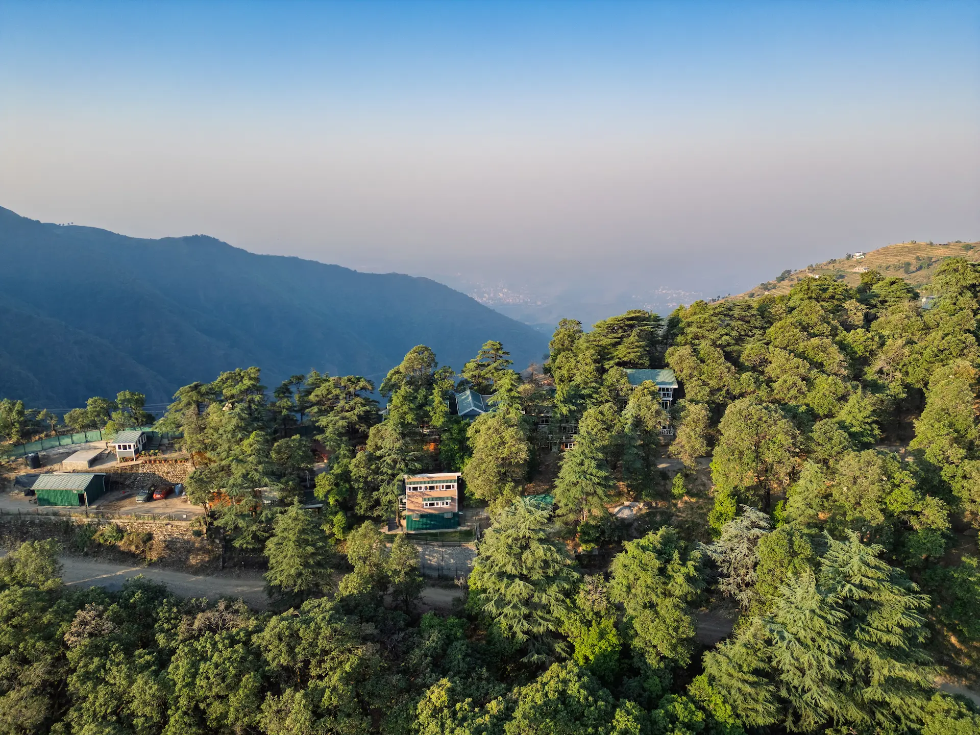 Aerial view of a forest retreat surrounded by pine trees and mountain valleys in Dhanaulti, Uttarakhand.