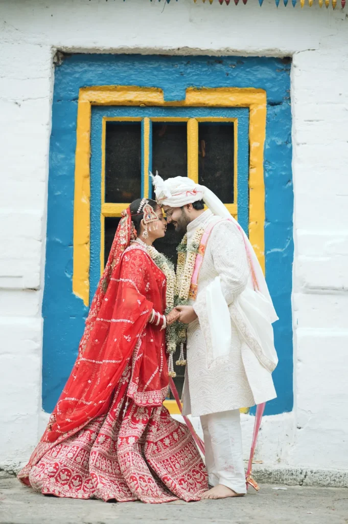 Bride and groom sharing an intimate wedding moment in the doorway of a traditional house in Triyuginarayan.