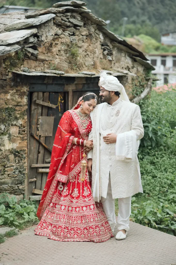 Bride and groom sharing a candid wedding moment beside a rustic stone house.