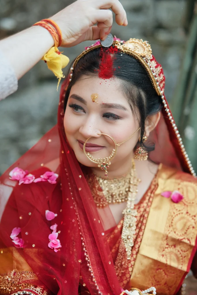 Groom applying sacred red sindoor to a smiling Indian bride's hair parting during their wedding at Triyuginarayan Temple.