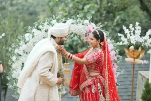Bride and groom sharing a playful wedding moment beneath a floral arch.