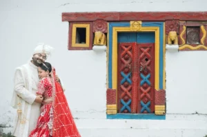 Bride and groom sharing an intimate wedding moment beside a colorful traditional house in Triyuginarayan.