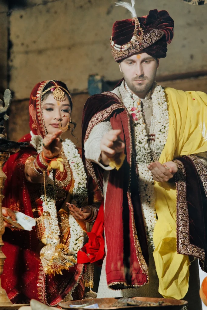Indian bride and groom in traditional attire performing a sacred wedding ritual offering at Triyuginarayan Temple.